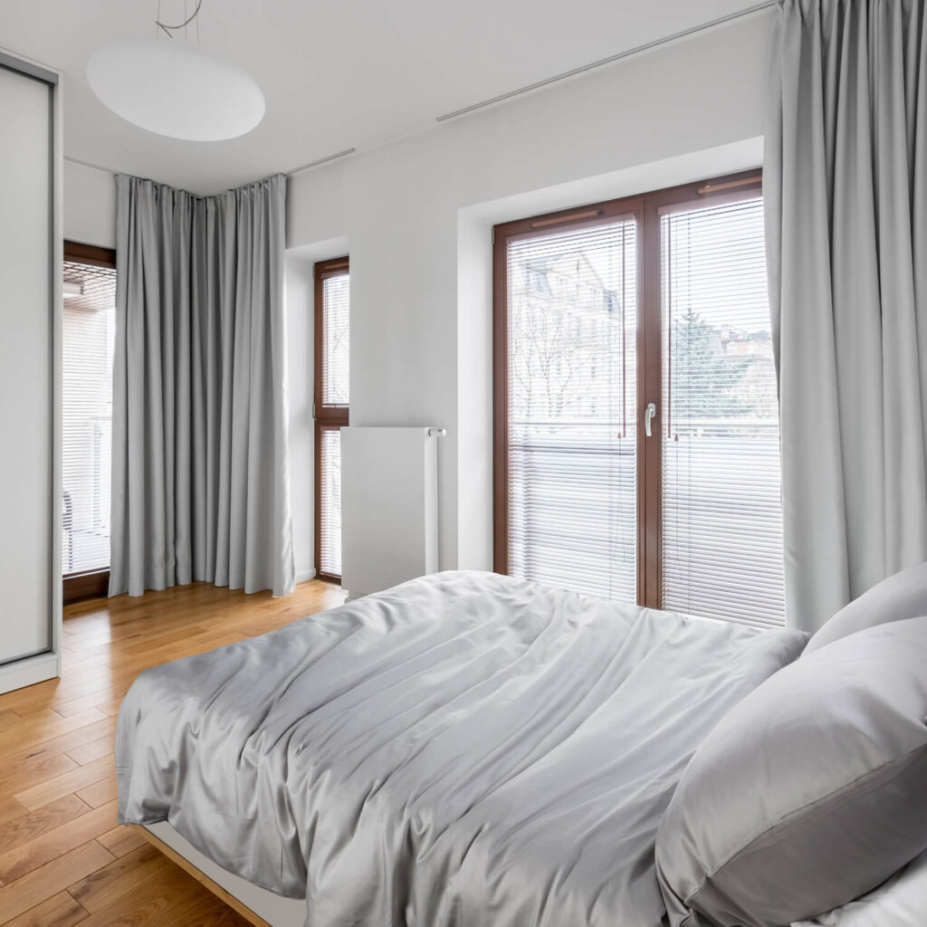 Temdančios pilkos užuolaidos miegamajame